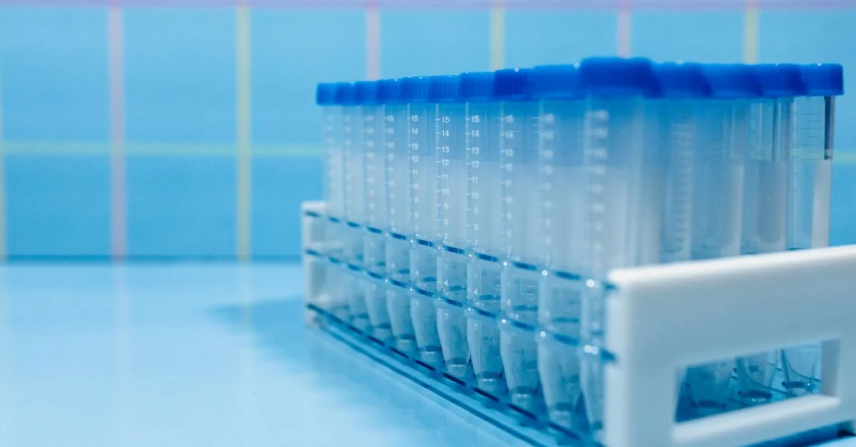 Des tubes à essai de laboratoire dans un support en plastique sur une surface bleue réfléchissante.
