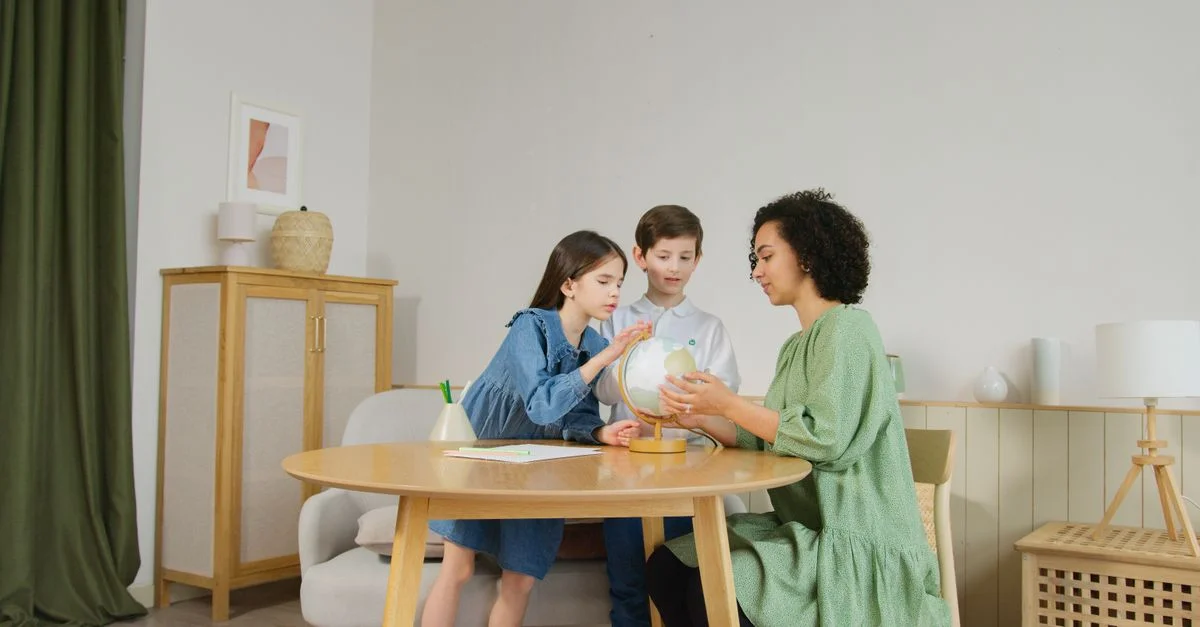 Deux enfants et un enseignant explorent un globe ensemble à l'intérieur, favorisant l'éducation.