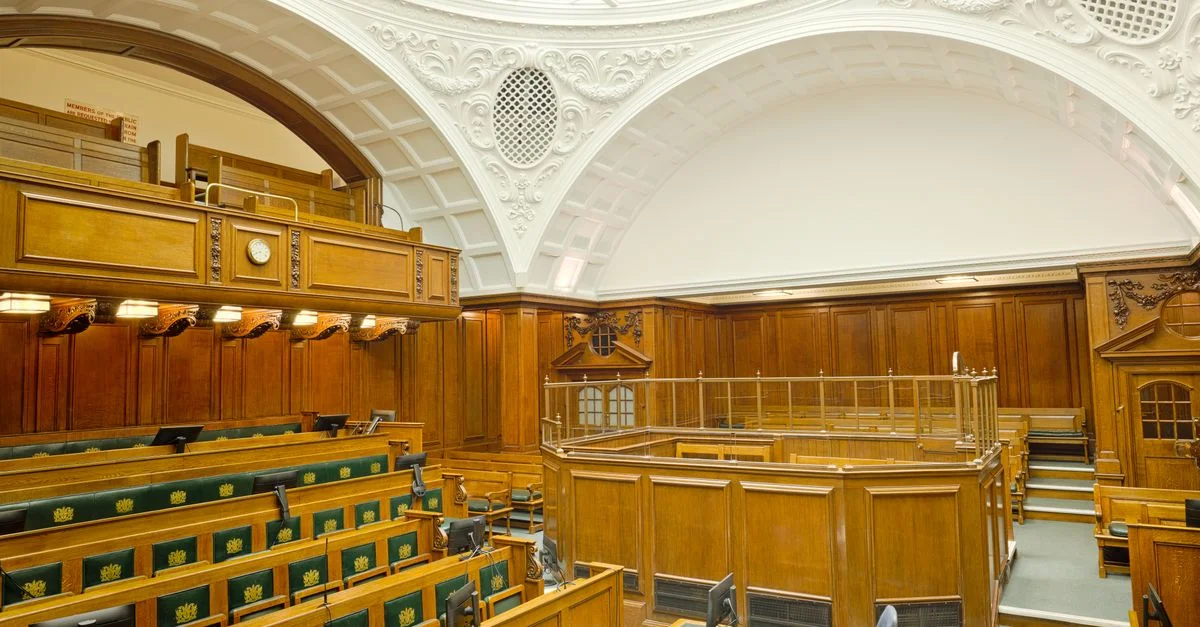 Vue intérieure d'une salle d'audience historique à Londres avec un design orné et un mobilier en bois.