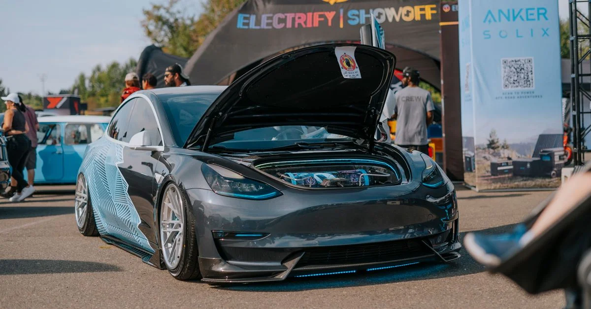 Voiture électrique exposée avec capot ouvert lors d'un événement automobile en plein air.