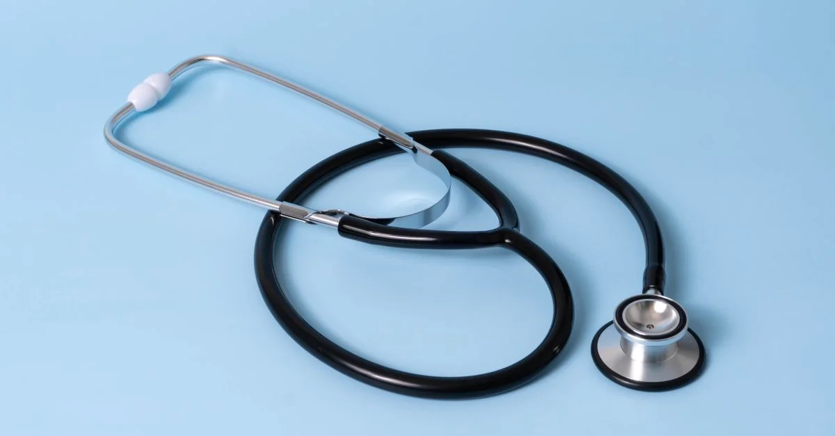 Gros plan d'un stéthoscope classique sur un fond bleu, symbolisant les soins de santé et la profession médicale.