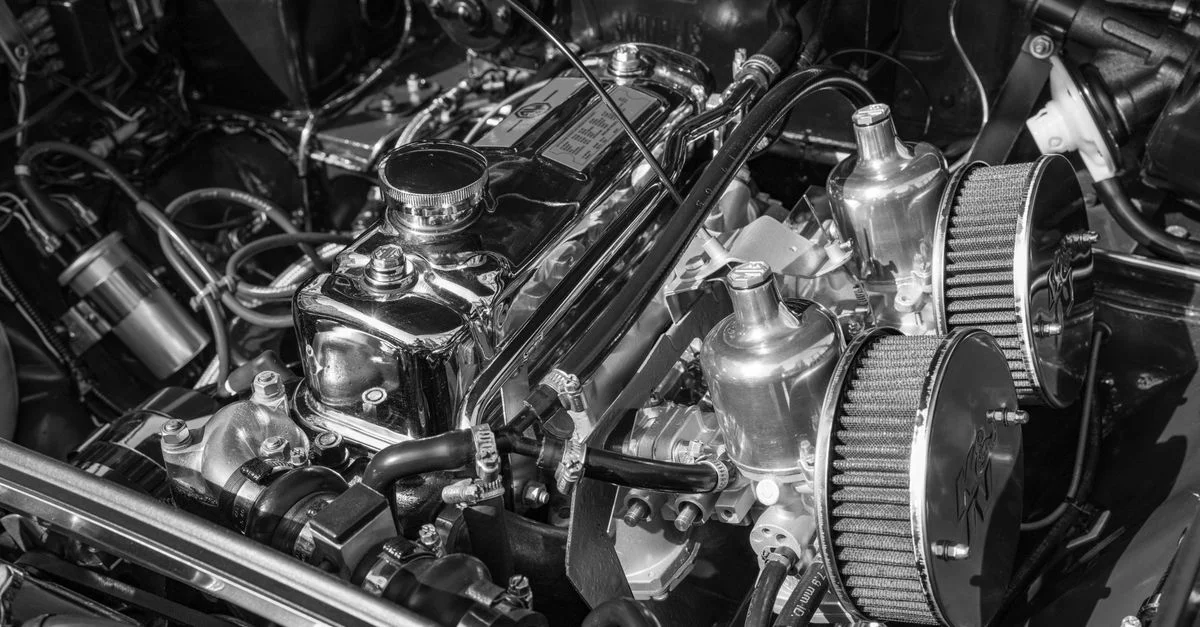 Gros plan détaillé d'un moteur de voiture classique, mettant en valeur les chromes et les composants mécaniques.