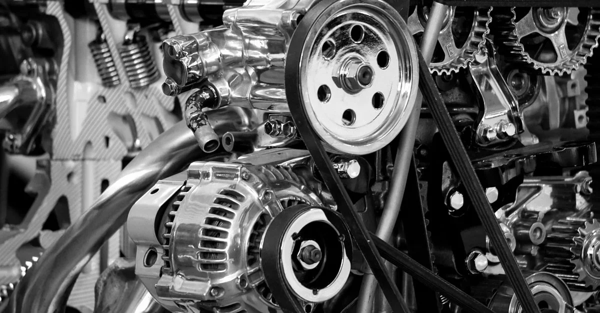 Gros plan sur un moteur de voiture brillant montrant des pièces métalliques polies et des engrenages en noir et blanc.