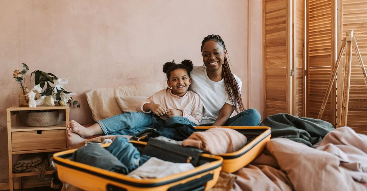 Mère et fille souriantes en train de faire les valises ensemble dans une pièce confortable.